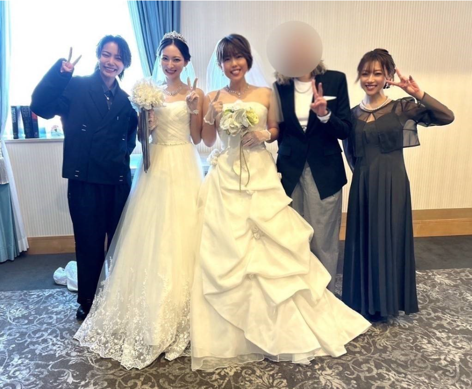 結婚式のドレスを着た女性二人と、友人３人が
並んでいる。
笑顔でポーズをとっている。